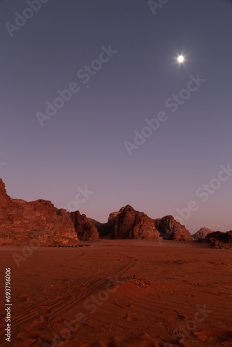 Moon shinning during red sunset upon the desert sand  Wadi Rum