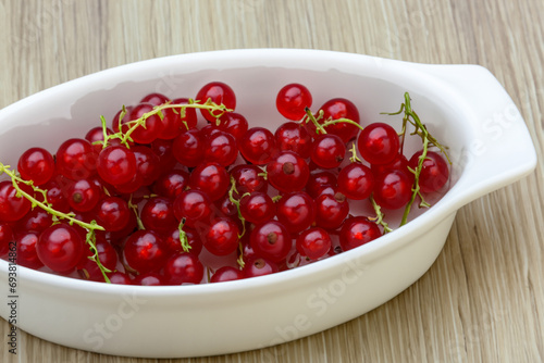 healthy berries. fresh bright red currant berry lies on a white deep plate, the plate stands on a wooden table, top view