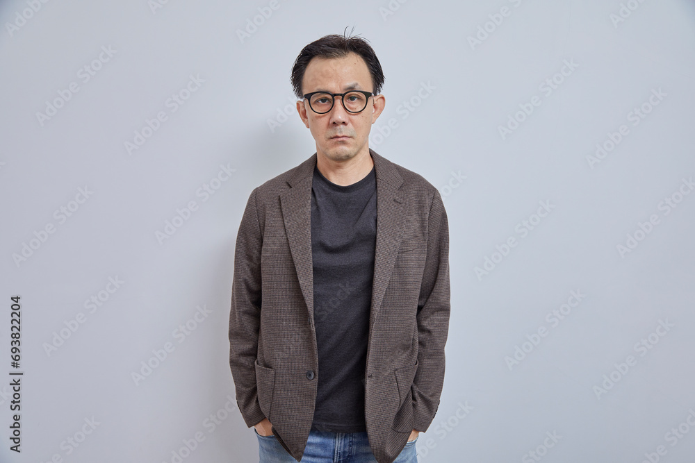 Obraz premium Handsome Asian businessman in suit with eyeglass smile and look at camera on grey background.