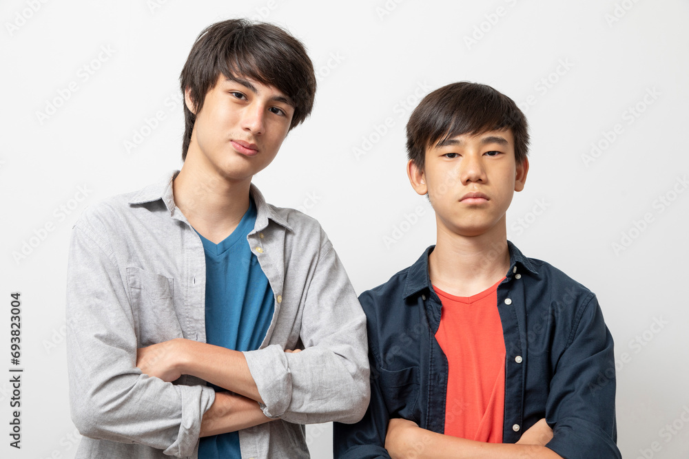 Caucasian and Asian teen boys wear shirt and stand on white background. Concept of mix raced. Caucasian and Asian teen boys wear shirt and stand on white background. Concept of mix raced.