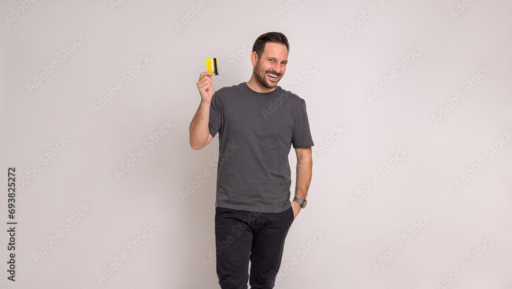 Happy male professional with hand in pocket laughing and showing credit card on white background Happy male professional with hand in pocket laughing and showing credit card on white background