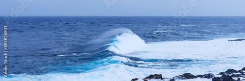 Panoramic image. Powerful blue ocean wave on the coast