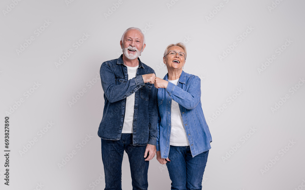 Portrait of happy senior couple screaming and giving fist bumps while standing on white background Portrait of happy senior couple screaming and giving fist bumps while standing on white background