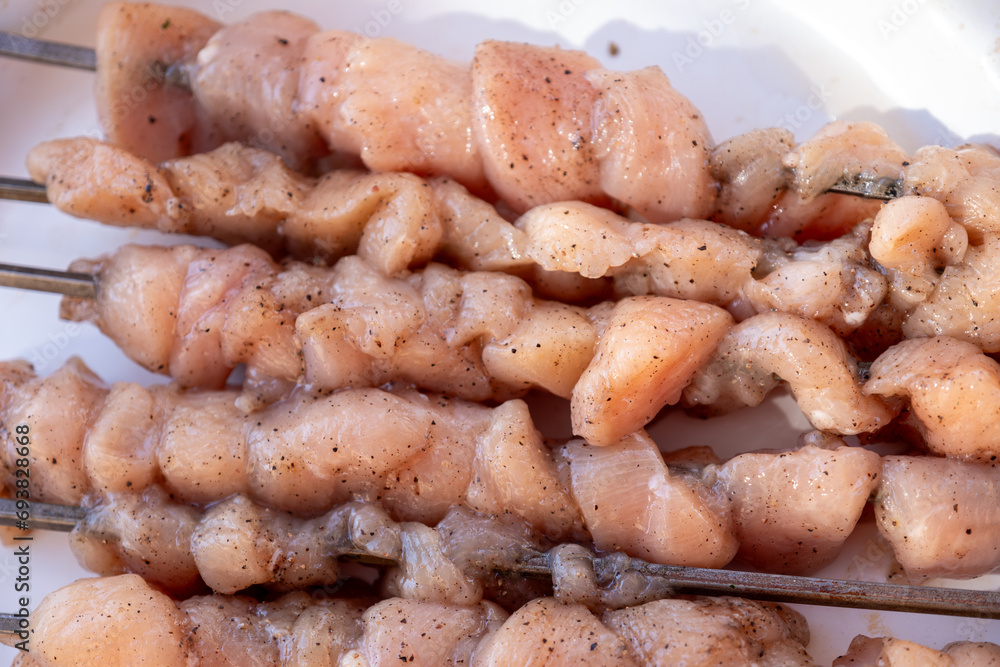 Raw chicken pieces are ready to be grilled over the fire and threaded into metal skewers Raw chicken pieces are ready to be grilled over the fire and threaded into metal skewers