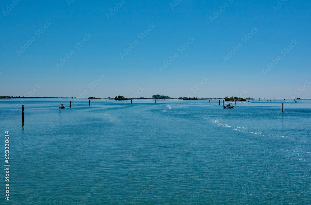 Markers show the edge of a navigable channel in the shallow waters in the Grado section of the Marano and Grado Lagoon in Friuli-Venezia Giulia, north east Italy. August