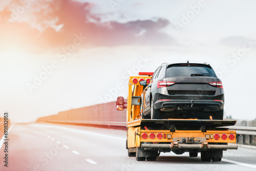 A broken car on the highway. A tow truck service helps a man with his damaged vehicle after a collision. tow truck transports a broken car on the road.
