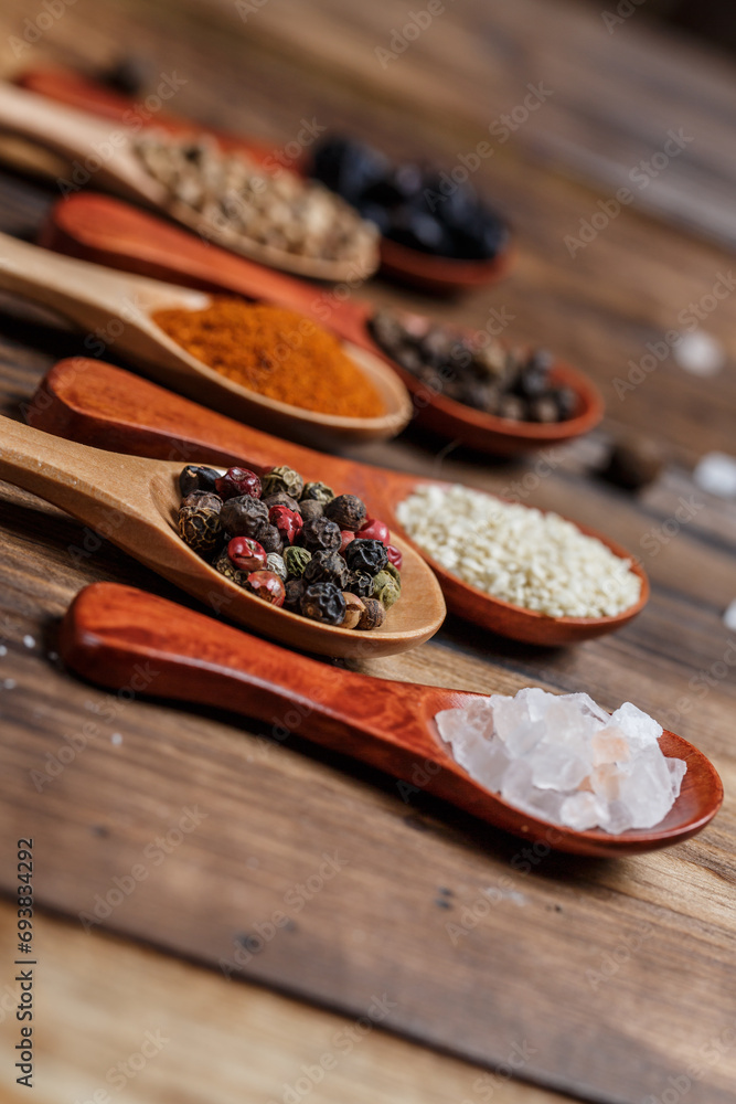 Many different spices in wooden spoons on a wooden background, background with spices, spices in spoons