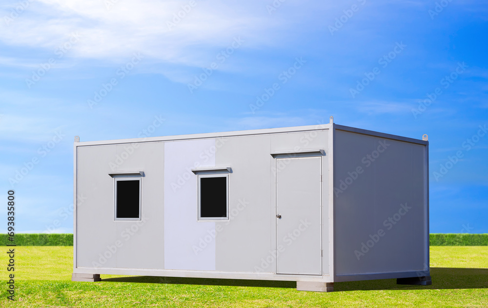 White mobile sandwich panel office container for rent and sale on green lawn with blue sky background White mobile sandwich panel office container for rent and sale on green lawn with blue sky background