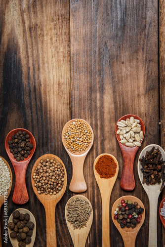 Many different spices in wooden spoons on a wooden background, background with spices, spices in spoons