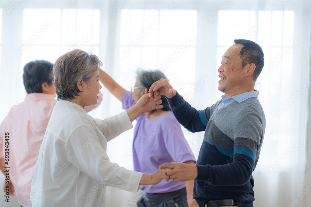 Asian Older male and females people dance with their partners on a dancing floor in living space. Happy older couple performing get exercise. Joyful carefree retired senior friends enjoying relaxation Asian Older male and females people dance with their partners on a dancing floor in living space. Happy older couple performing get exercise. Joyful carefree retired senior friends enjoying relaxation