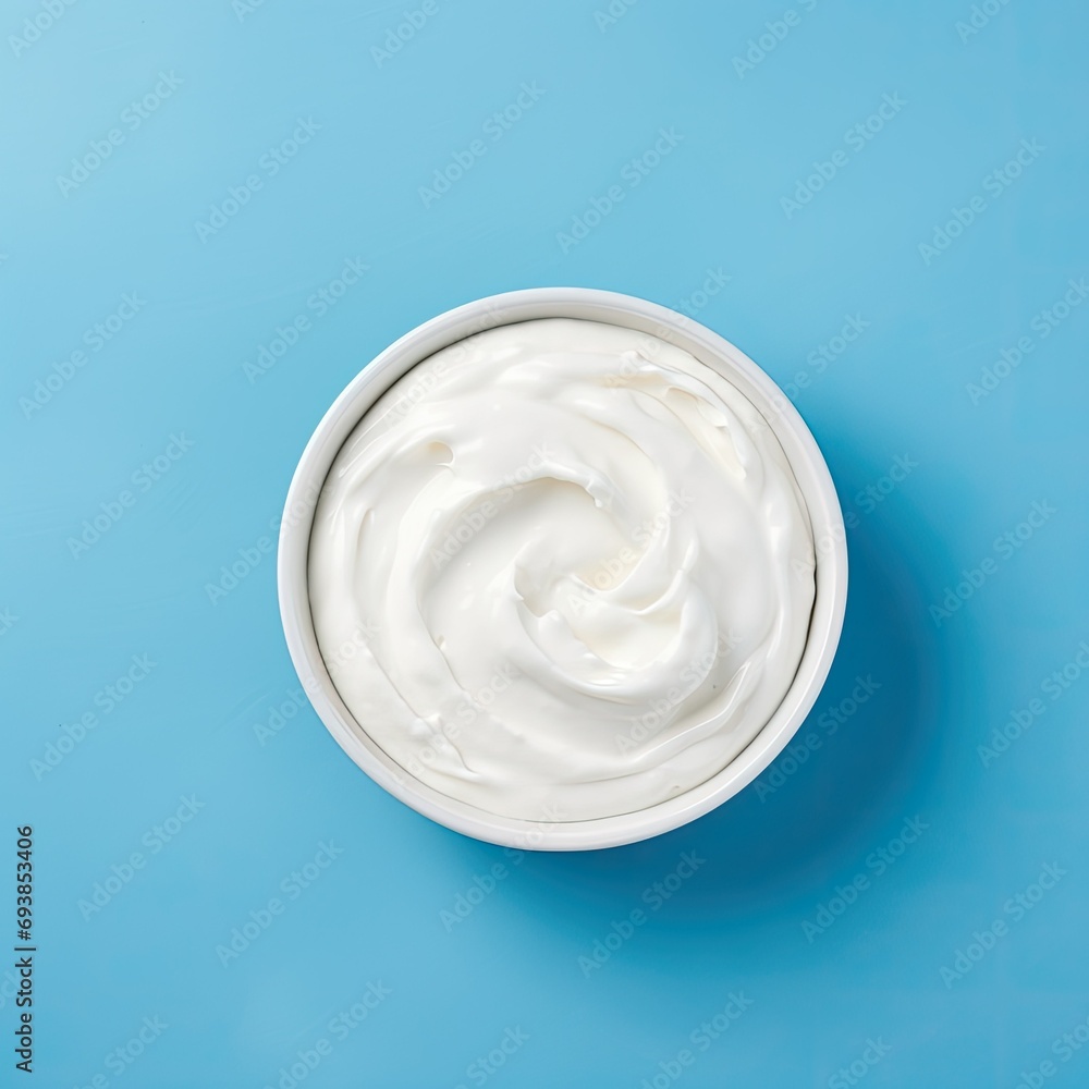 Top view of bowl with white cream on blue background side Top view of bowl with white cream on blue background side