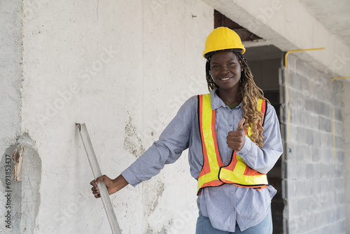 African American foreman builder woman at construction site. Foreman construction woman working at construction site, wearing safety uniform and helmet photo