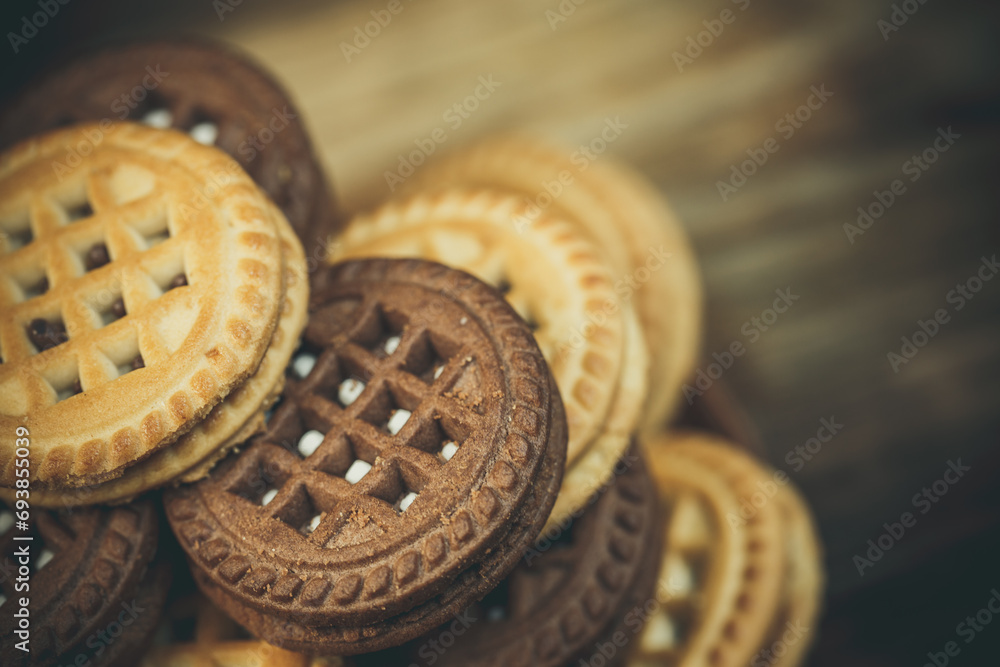 Chocolate and vanilla round cookies on a wooden table with a cup of coffee, round cookies on the table, New Year's treats and holiday mood Chocolate and vanilla round cookies on a wooden table with a cup of coffee, round cookies on the table, New Year's treats and holiday mood