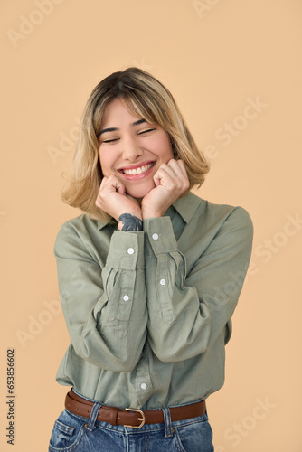 Pretty gen z blonde young woman, cute student girl with short blond hair wearing khaki shirt and jeans feeling happy laughing standing isolated on beige background. Vertical shot.