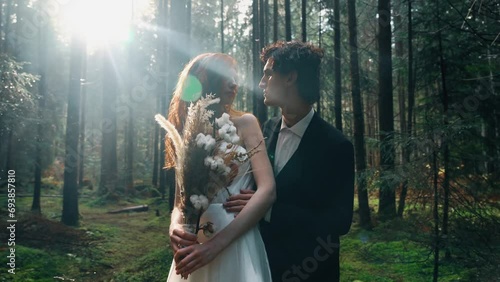 A bride with red hair poses with the groom in a pine forest. Fairytale wedding couple. Wedding concept photo