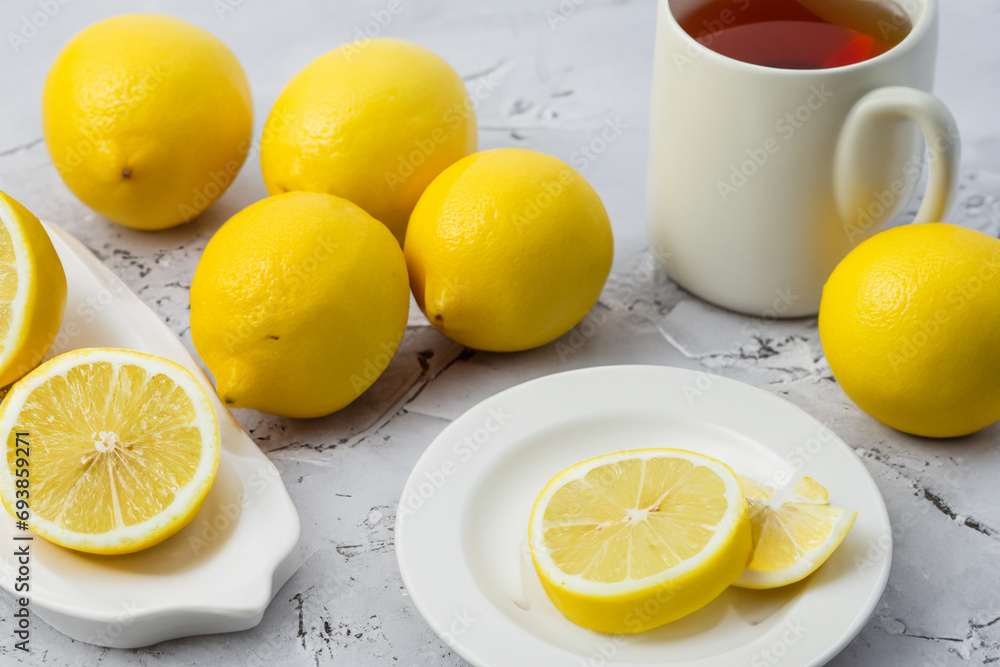 vitamin composition. on a wooden table there is a small mug of tea next to there are a large number of yellow lemons vitamin composition. on a wooden table there is a small mug of tea next to there are a large number of yellow lemons