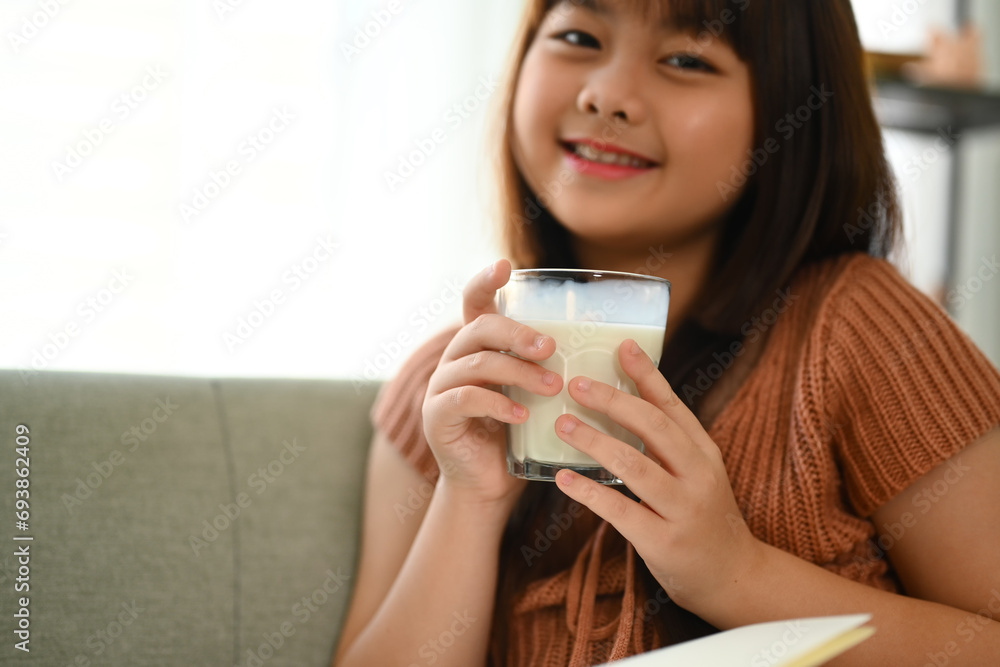 Happy little Asian schoolgirl drinking milk for good health and looking at camera Happy little Asian schoolgirl drinking milk for good health and looking at camera