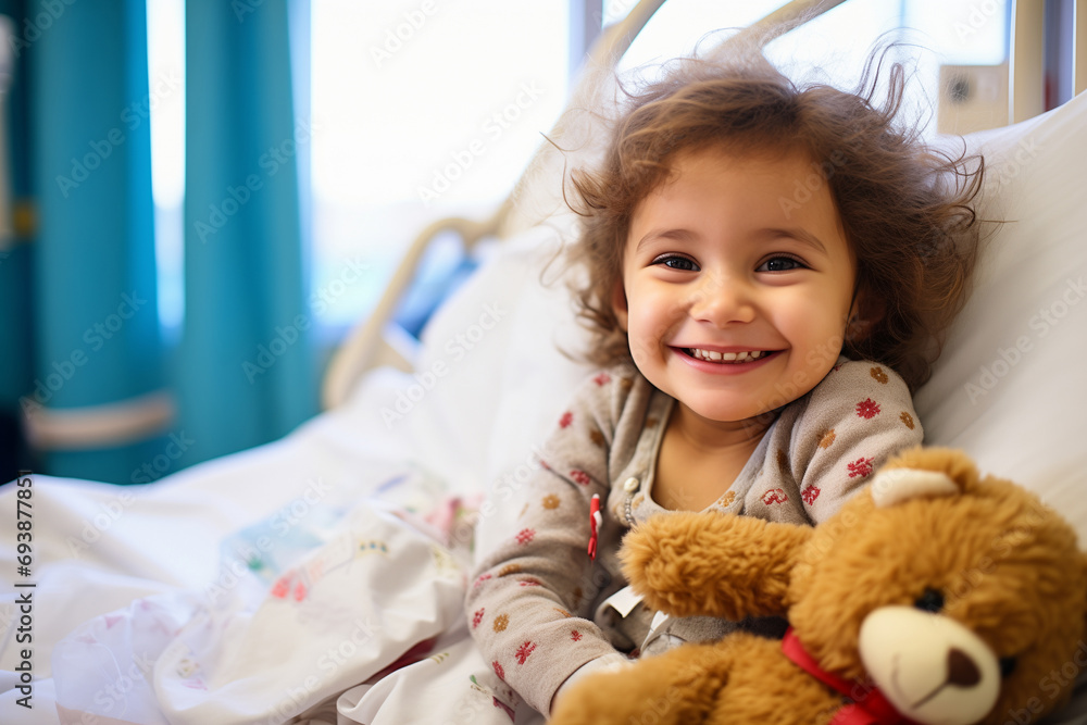 Little child with a teddy bear lying on a hospital bed in pediatrics Little child with a teddy bear lying on a hospital bed in pediatrics