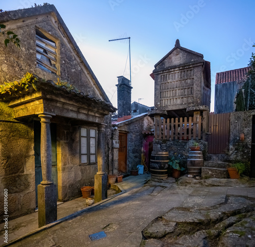 Quaint old European street with traditional stone buildings and a unique wooden granary at dusk.