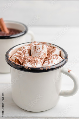 Homemade spicy hot chocolate drink with white marshmallows in enamel cup on wooden table