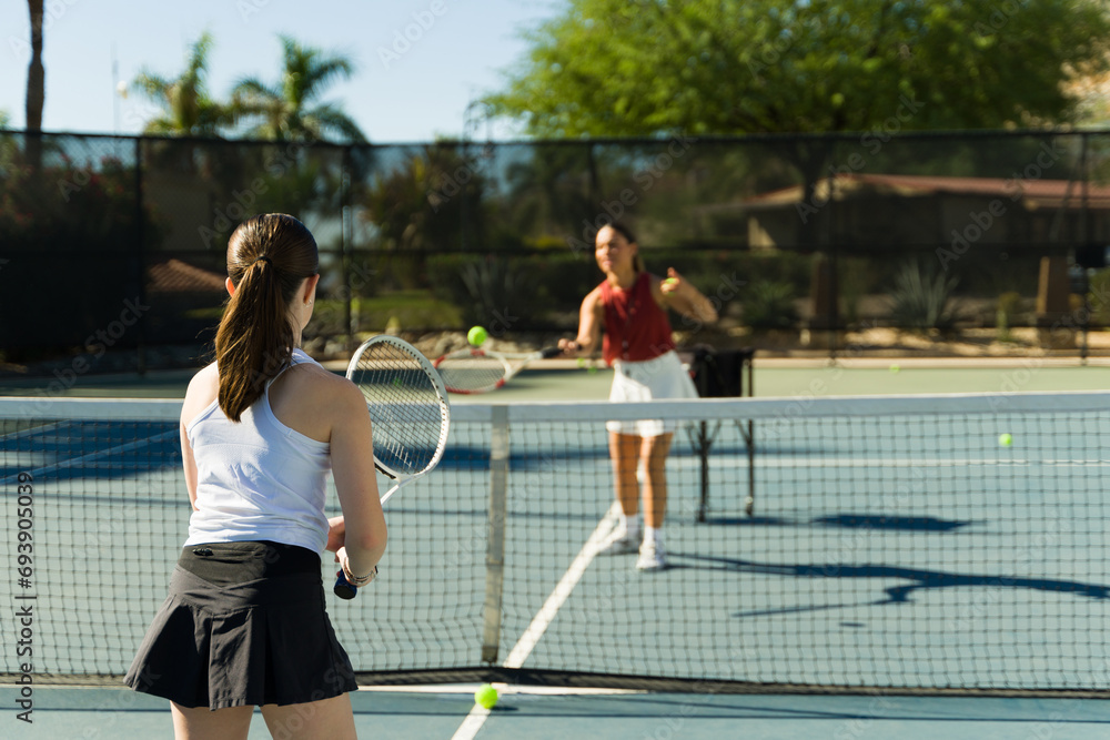 Caucasian teen girl seen from behind playing a tennis match Caucasian teen girl seen from behind playing a tennis match