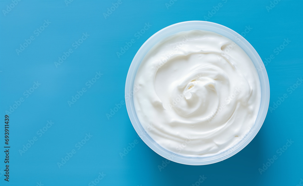 Top view of bowl with white quark or cream on side of blue background Top view of bowl with white quark or cream on side of blue background