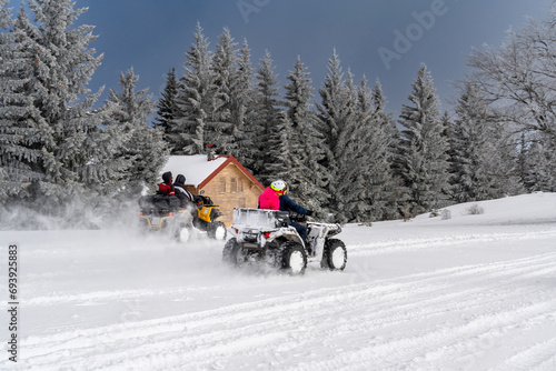 Winter race on an ATV on snow in the forest. Quad bike in motion, ride on top of the mountain on snow. People riding quad bike in the forest.