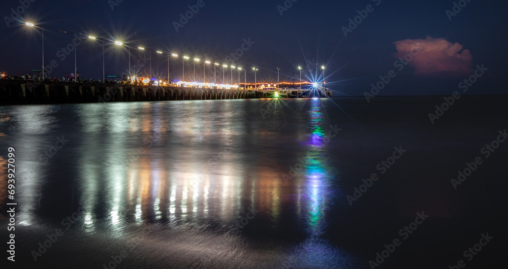 Long exposure shot of a pier at night time by the sea