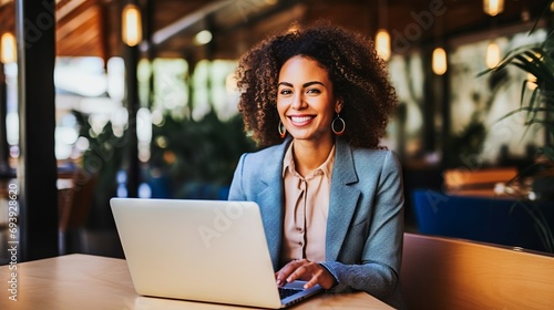 Confident and smiling business woman working on laptop in modern office photo