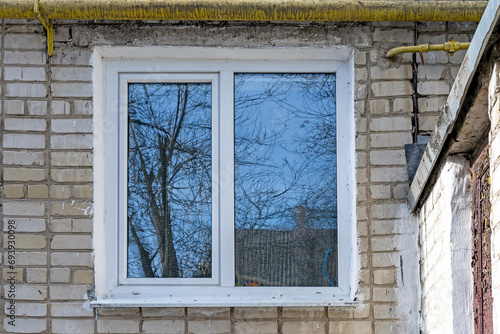 White PVC double casement window with blue sky reflection. Brick wall