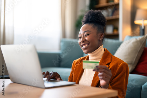 Cheerful businesswoman holding credit card and shopping online over laptop at home office. photo