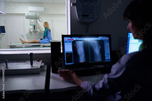 Experienced radiographer is performing digital lower limb radiography on patient photo