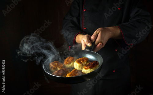 The chef fries donuts in a frying pan. The concept of preparing a Polish national dish in a restaurant kitchen. Black space for recipe or menu