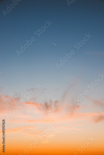 Colourful sky during sunset with reddish hues. Blue, orange and golden sky. Airplane flying over in red sun. Abstract sky