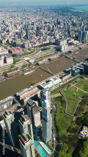 Vertical Aerial drone view of Puerto Madero harbor with Puente de la Mujer bridge and skyscraper buildings in the background. Buenos Aires, Argentina.
 photo