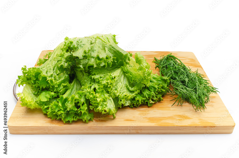 Green salad leaves and a bunch of dill on a wooden cutting board. Side view. Fragrant greens. Green salad leaves and a bunch of dill on a wooden cutting board. Side view. Fragrant greens.