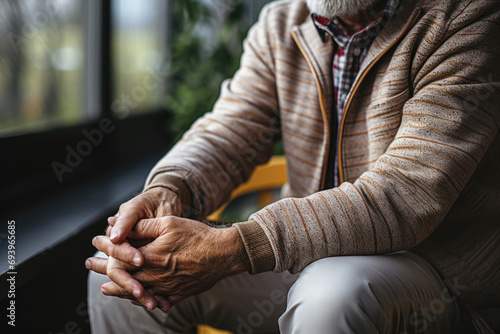 Close-up of folded hands of a seated elderly man. Old age, senile diseases concept. photo