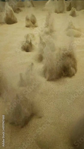 Sand surface exploding randomly with blasts effects. Sandy background blowing and impact shock pattern. Dangerous environment. photo