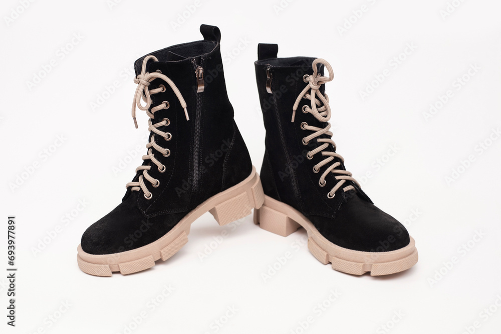 Black women's boots with beige high soles and beige laces, warm women's shoes on a light background