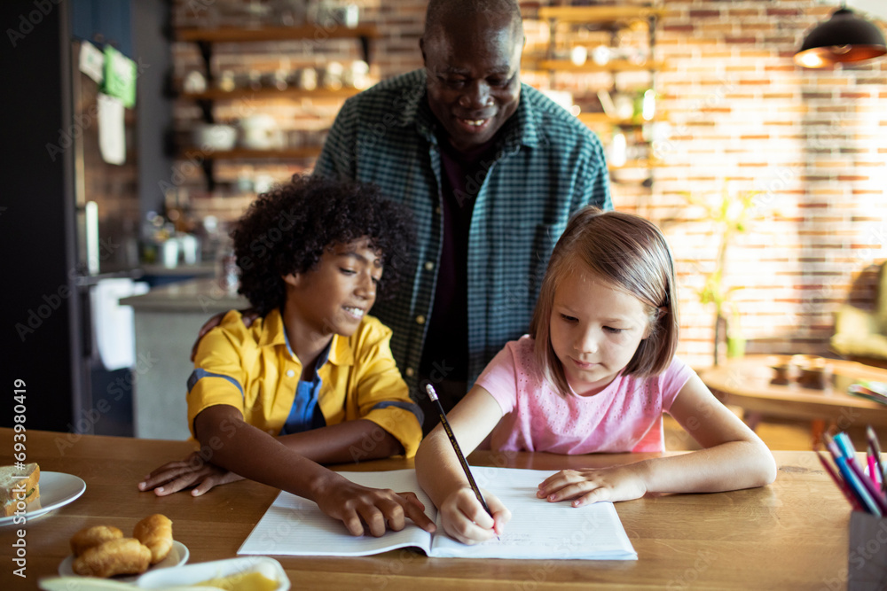 Father helping his diverse children with homework at home Father helping his diverse children with homework at home