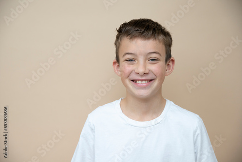 cool 11 years old boy with white t-shirt  in front of brown background in the studio photo