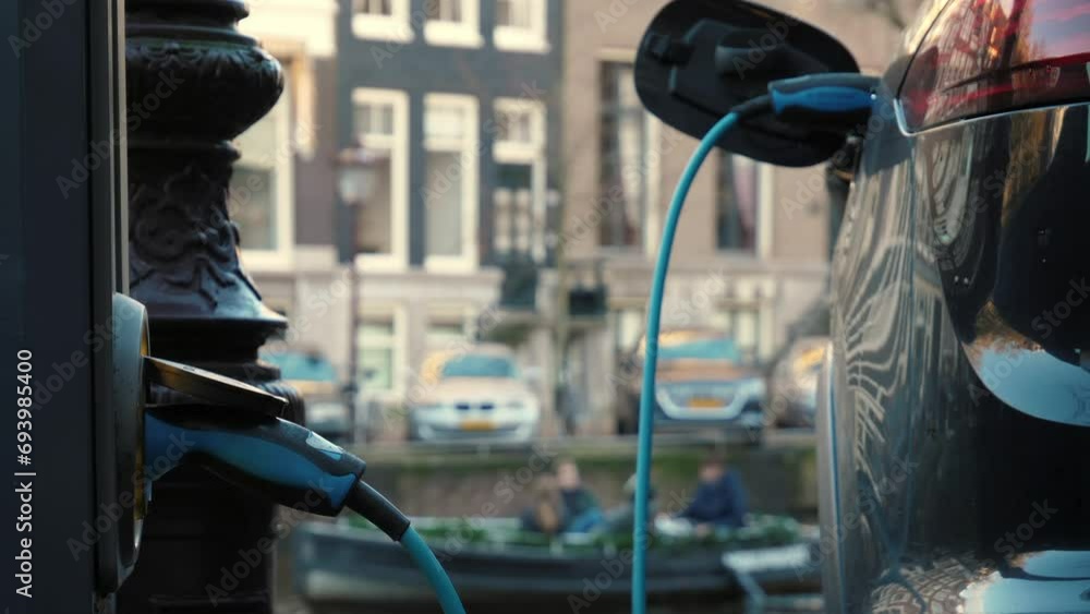 Electric vehicle plugged in with EV charger device from blurred ...