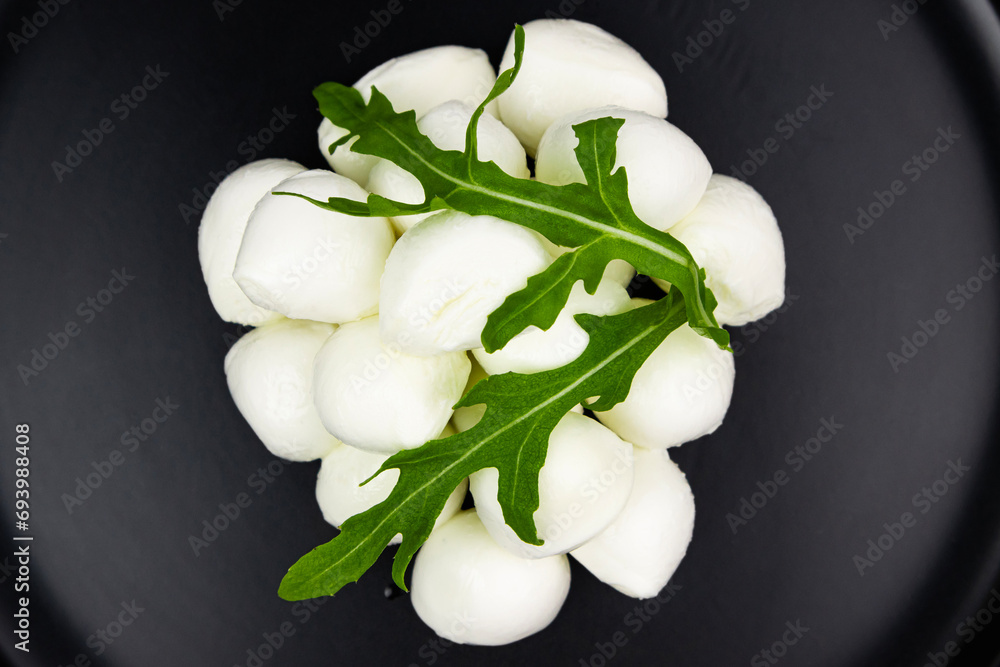 Mozzarella cheese with arugula leaves close-up on a black plate