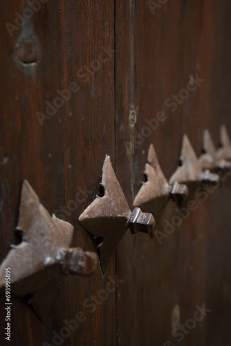 Ancient medieval wooden riveted door with protective iron details. Background on historical theme. Vertical image.