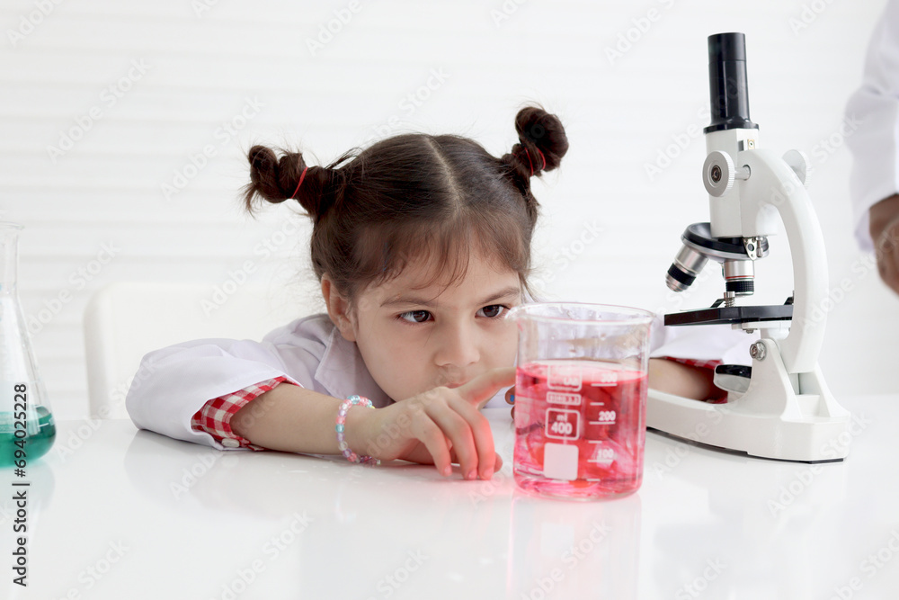 Cute little girl in lab coat doing science experiment at class room, young schoolgirl scientist kid having fun in chemistry laboratory class, little children doing research at school. Cute little girl in lab coat doing science experiment at class room, young schoolgirl scientist kid having fun in chemistry laboratory class, little children doing research at school.