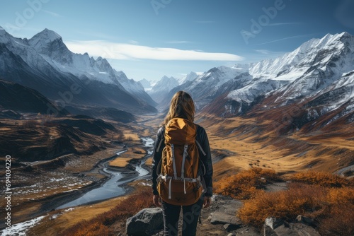 A lone figure stands atop a snow-covered mountain, gazing out at the vast expanse of nature below, their clothing blending seamlessly with the rugged landscape and the clouds above