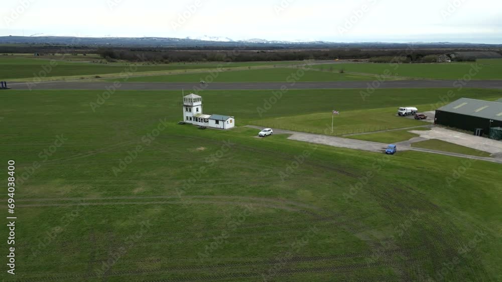 Small Regional Airfield Control Tower with british uk flag on flagpole runway green grass aviation Small Regional Airfield Control Tower with british uk flag on flagpole runway green grass aviation