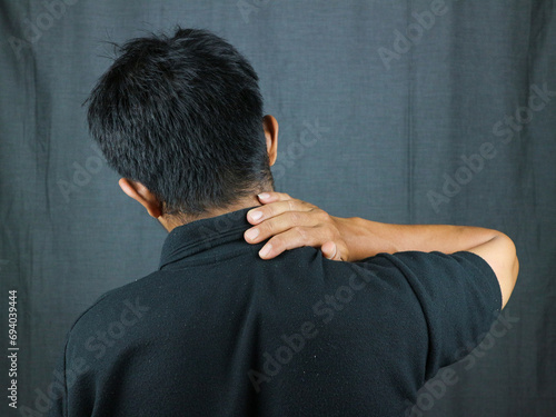 Close-up rear view of man's hand touching shoulder pain, shoulder pain concept. photo