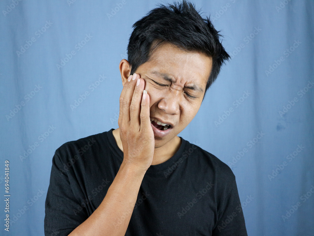 Pain expression of young asian man holding cheek because of toothache. toothache concept