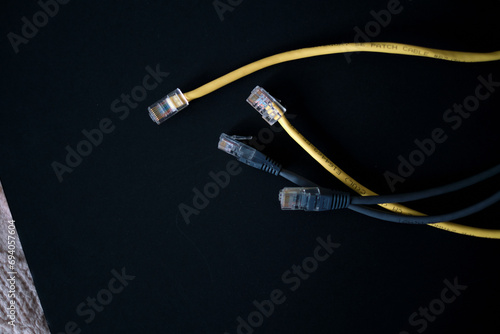 Ethernet cables with gold-plated connectors rest on a dark surface, symbolizing the backbone of wired internet connectivity.